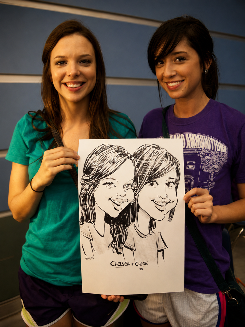 Two coworkers holding a duo caricature at a corporate team building event
