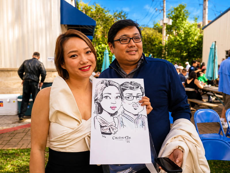 Couple holding a duo caricature at an evening community block party